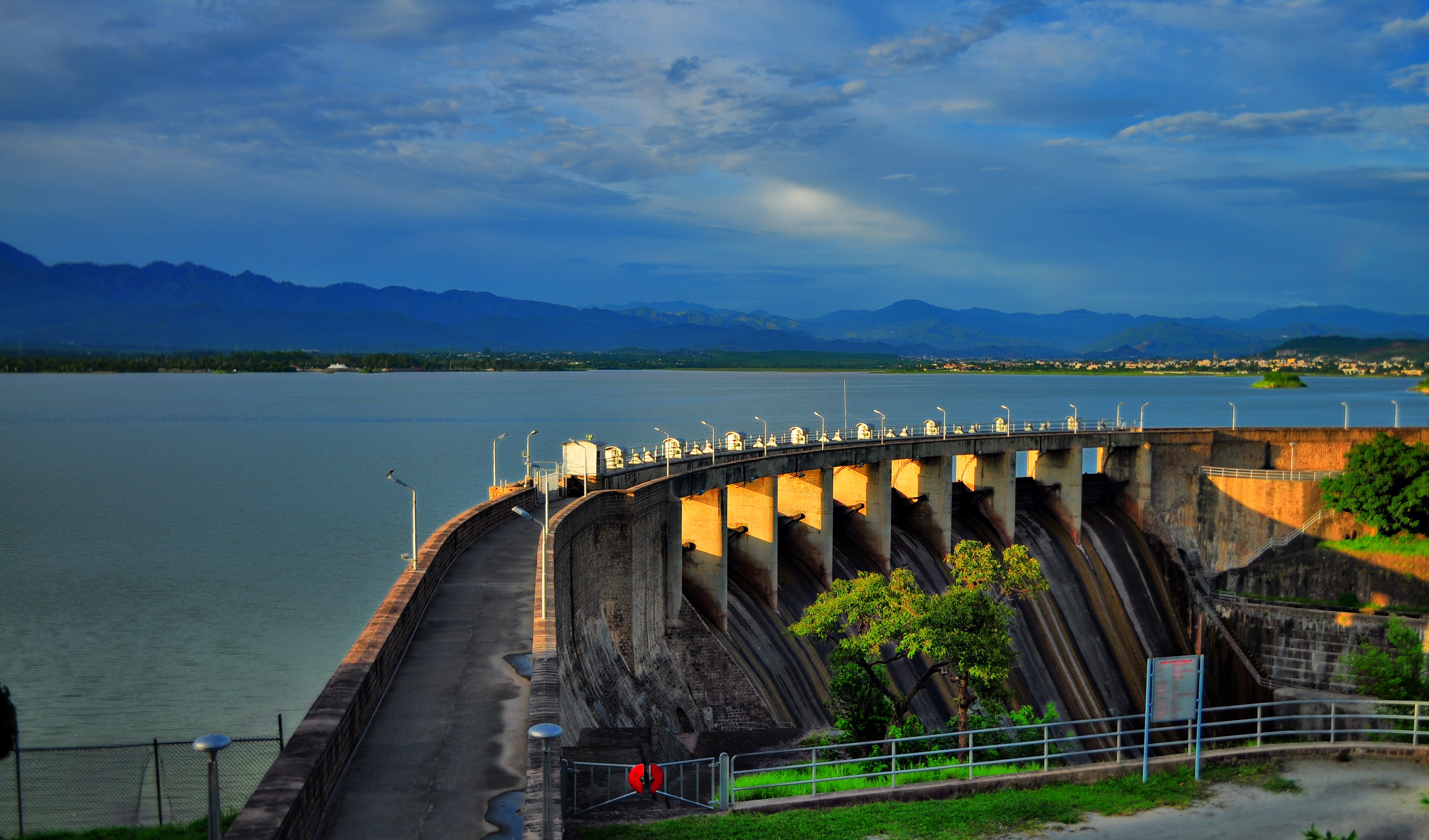Rawal Dam's spillway channels and reservoir near Islamabad under afternoon light.