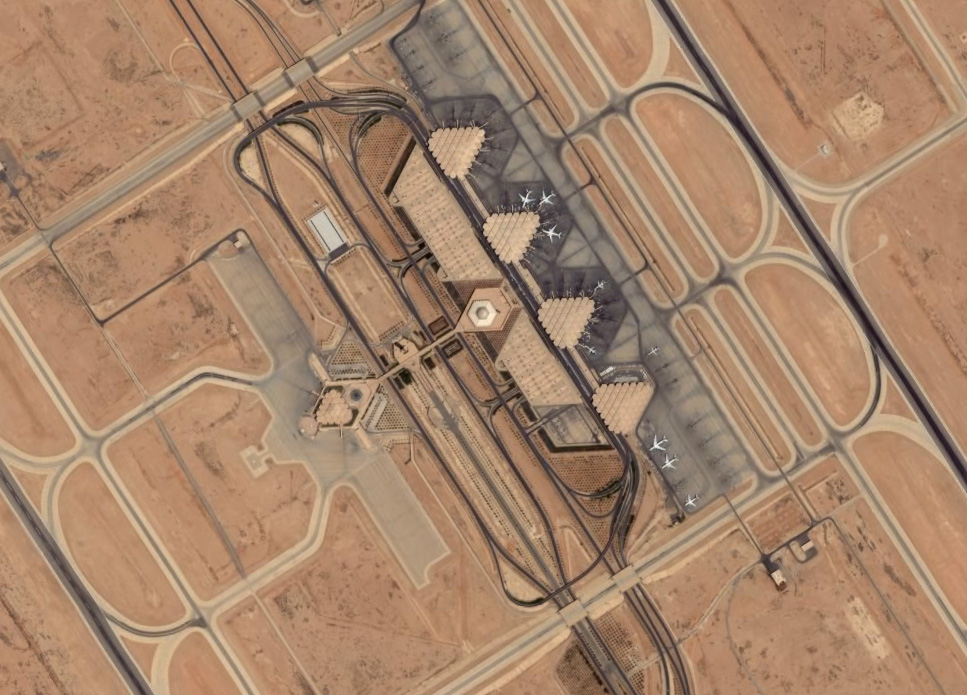 An aerial satellite view of King Khalid International Airport outside Riyadh, showing the runways, terminal buildings and surrounding desert.