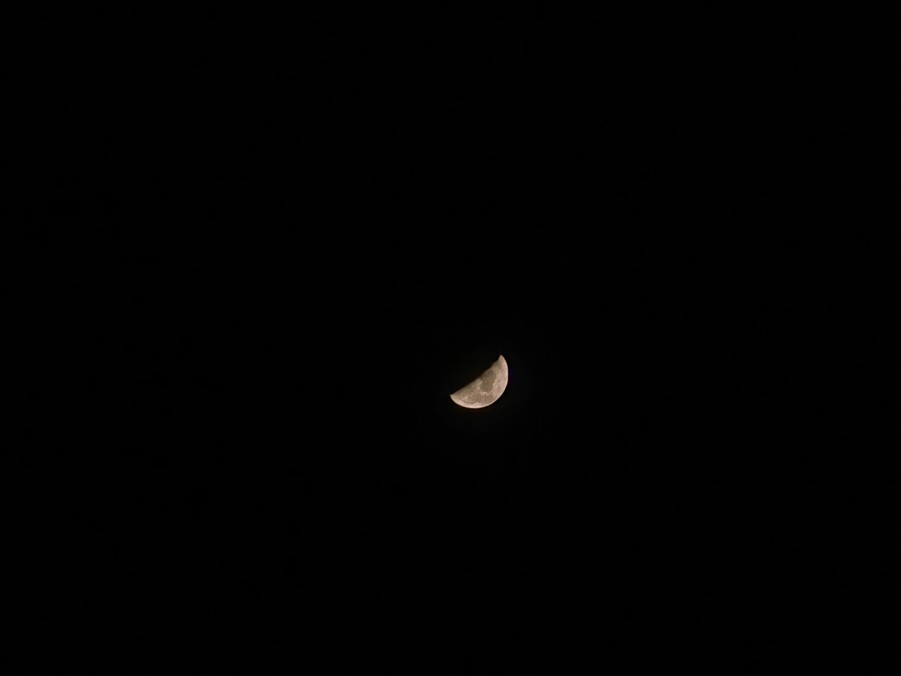 A thin crescent moon shining against a dark night sky.