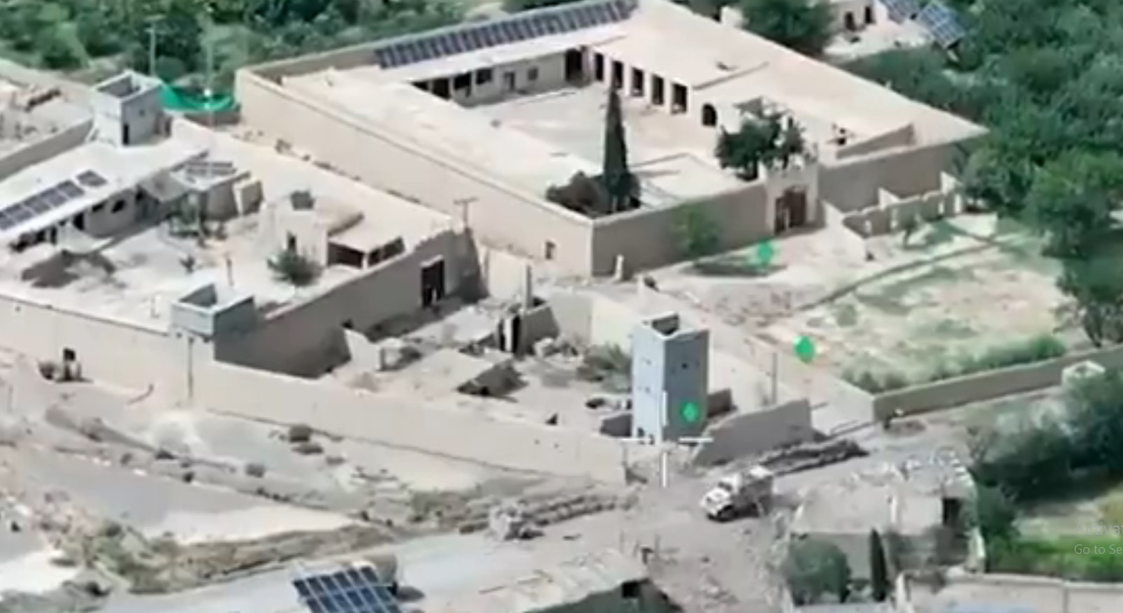 Aerial view of a walled security compound with a watchtower and solar panels.