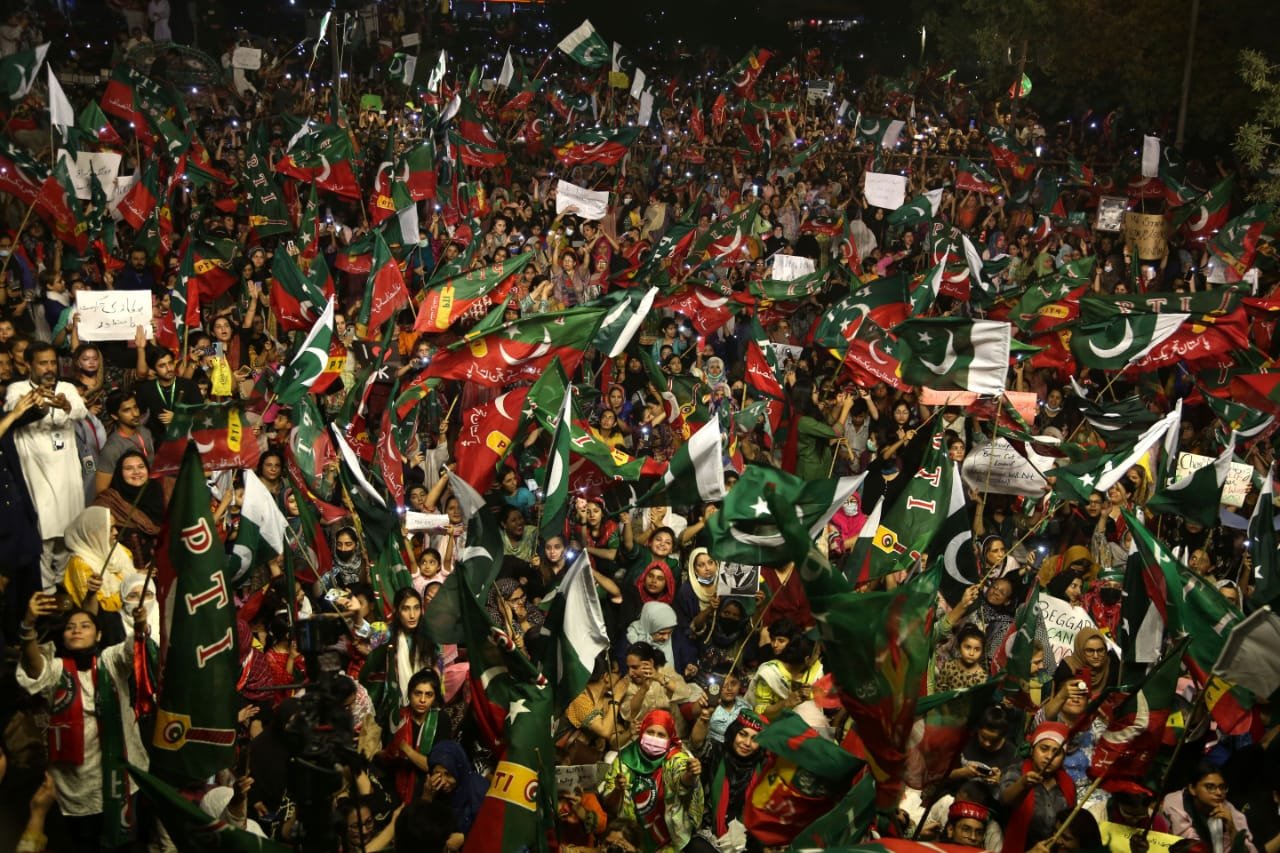 A crowd of protesters holding flags and banners at an outdoor political demonstration