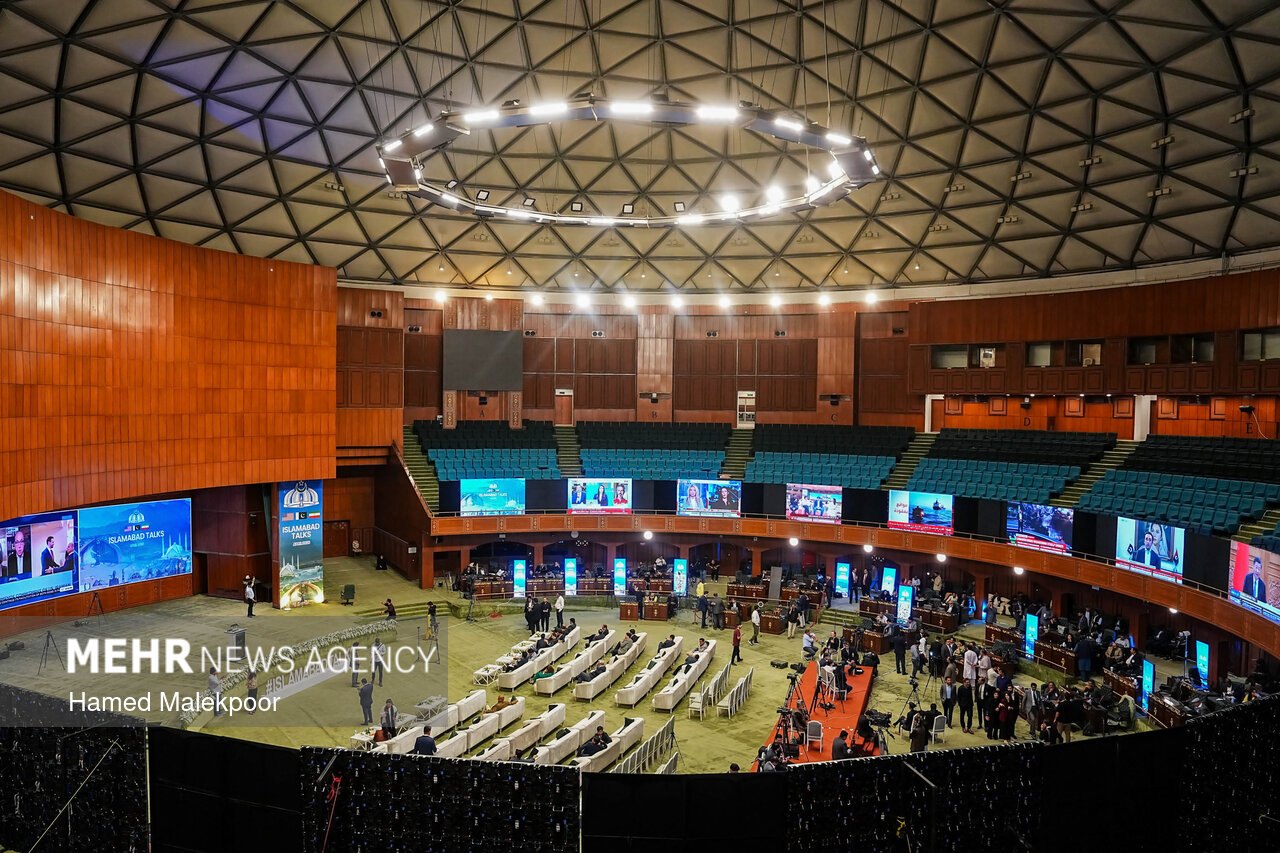 A wide view of the plenary hall prepared for the US-Iran Islamabad Talks, with blue 'Islamabad Talks' banners and large media screens.