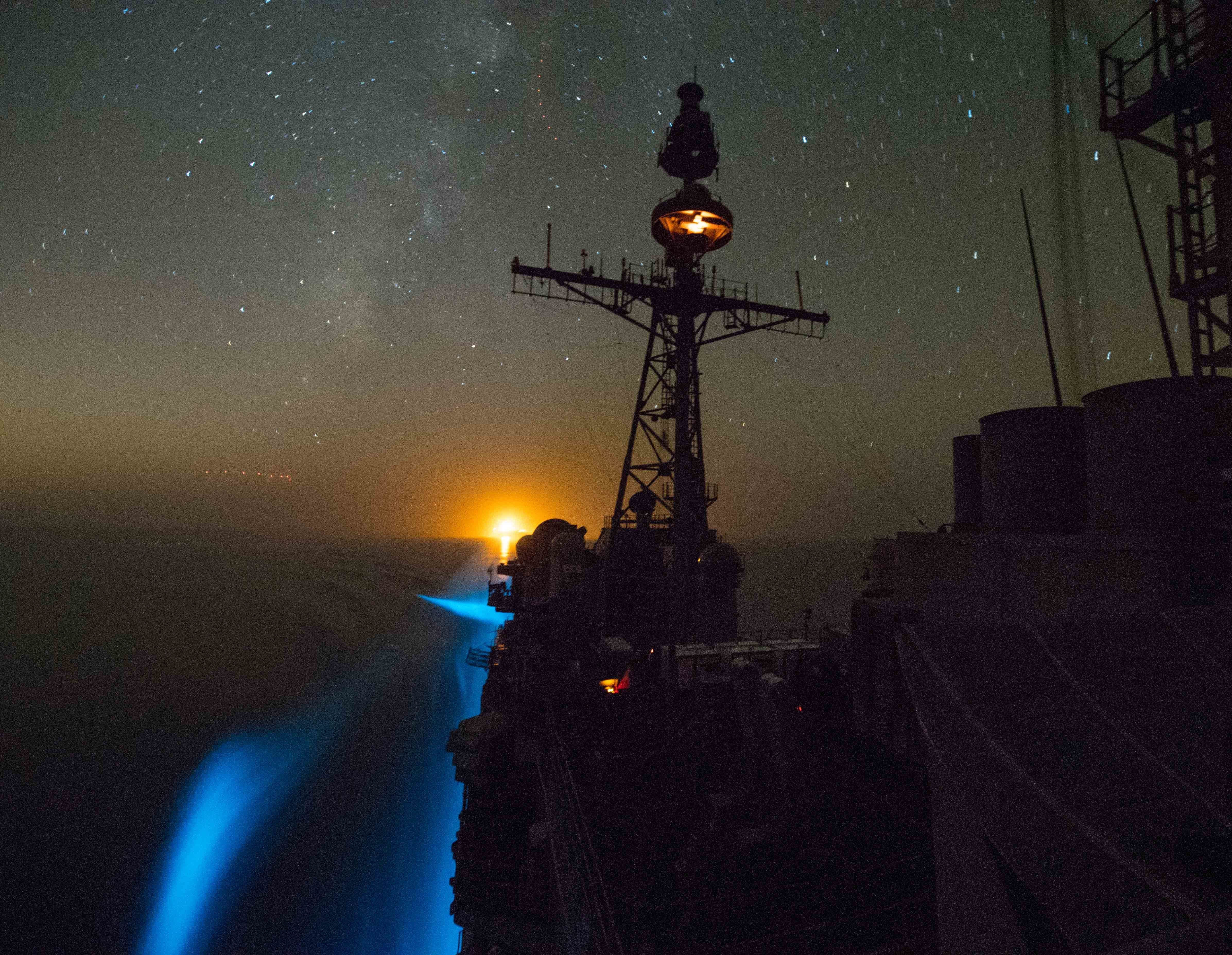 The US Navy guided-missile cruiser USS Princeton transits the Strait of Hormuz at night, photographed from a low angle