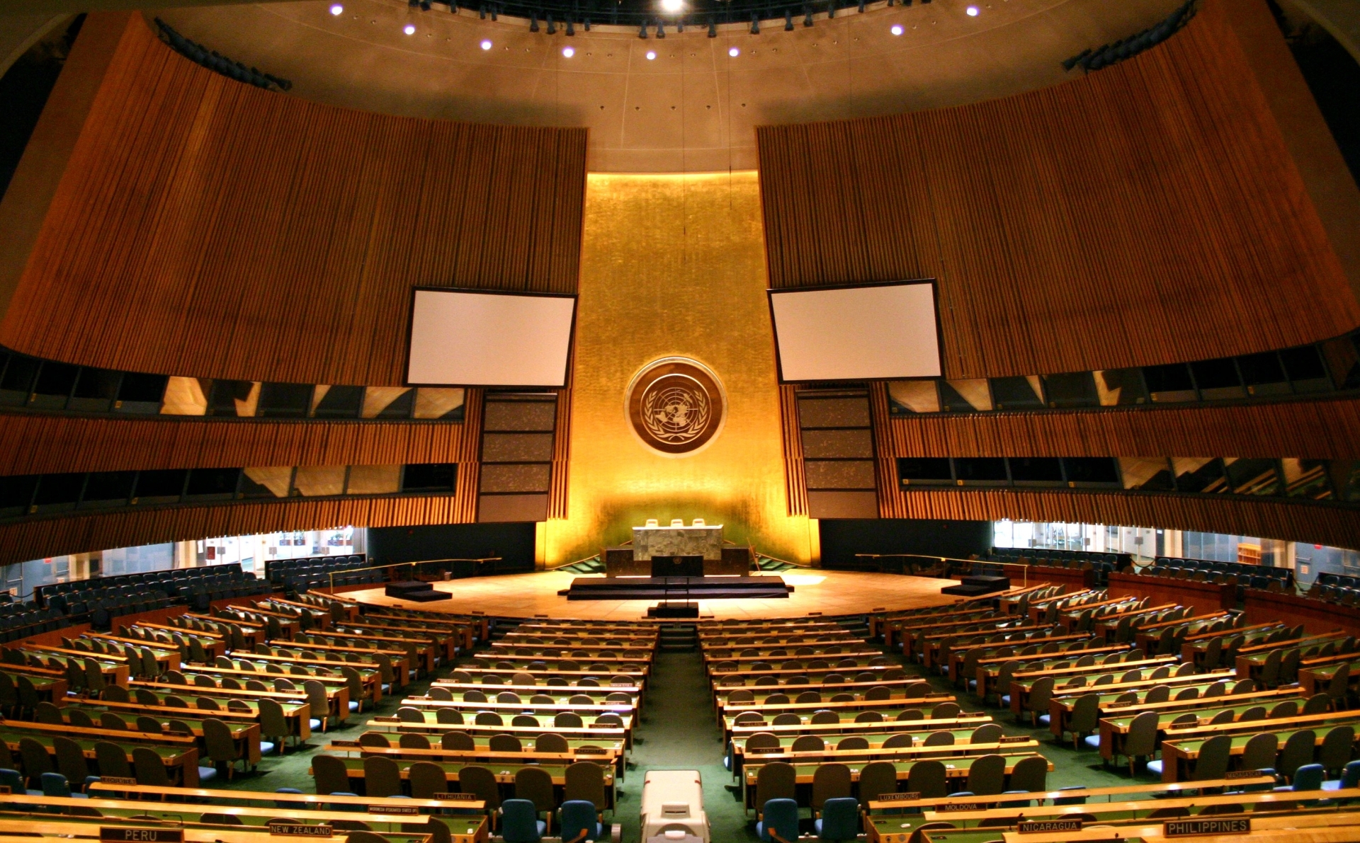 Interior of the United Nations General Assembly hall in New York, showing the marble stage, pale green walls and rows of seated delegates