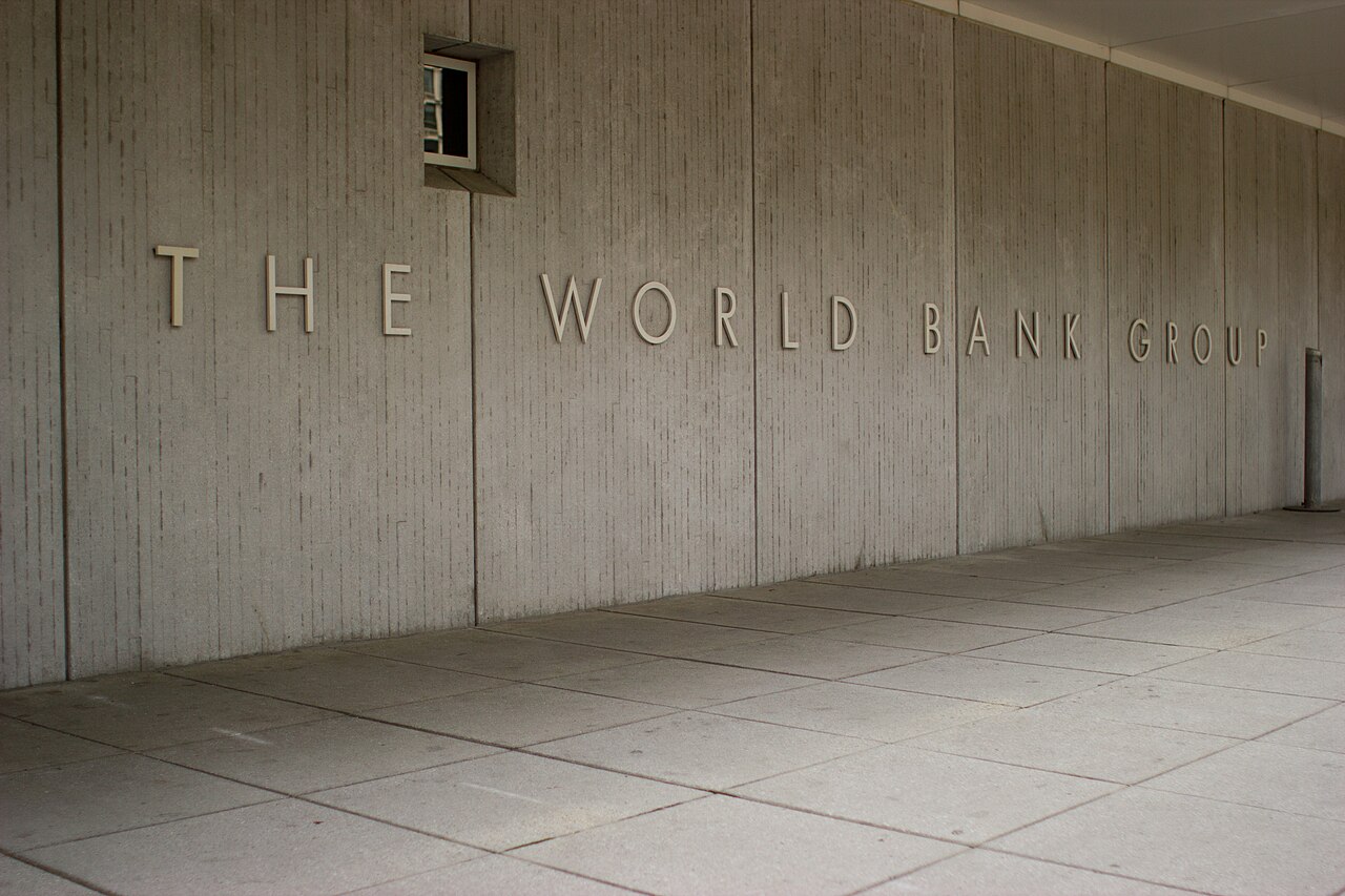 The entrance sign of the World Bank Group headquarters building in Washington, D.C., seen between two office towers in daylight.