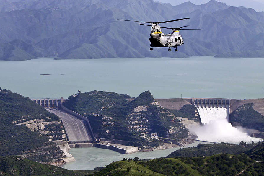 A helicopter flies over the Tarbela Dam reservoir on the Indus River with spillway water visible below